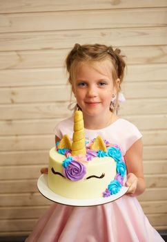 girl holding a cake in the form of a Unicorn.