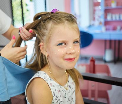 Hairdressing services. Reating hairstyle. Hair styling process. Children hairdressing salon.