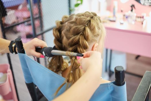 Hairdressing services. Reating hairstyle. Hair styling process. Children hairdressing salon.