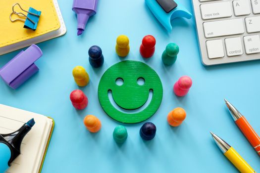 A Smiley surrounded by colored figures on the table. Employee satisfaction concept.