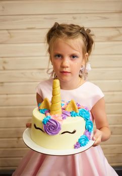 girl holding a cake in the form of a Unicorn.