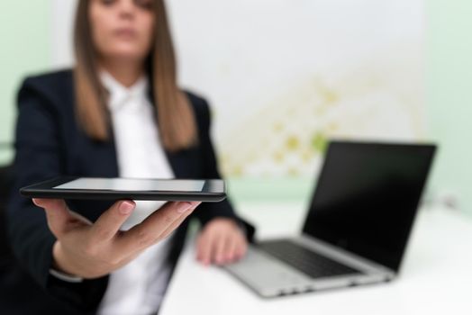 Businesswoman Holding Tablet With One Hand And Having Lap Top On Desk.
