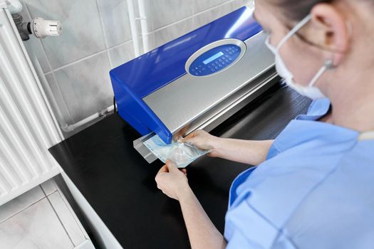 Cropped photo of a unrecognizable nurse using a pouch heat-sealing machine to sterilise material