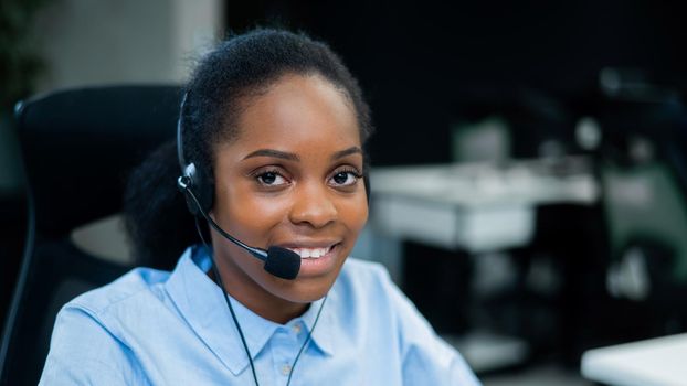 African young woman talking to a client on a headset. Female employee of the call center