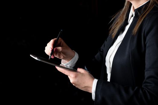 Businesswoman Holding Tablet In One Hand And Pointing With Pen On It