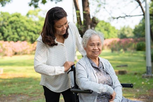 Caregiver help and care Asian senior or elderly old lady woman patient sitting and happy on wheelchair in park, healthy strong medical concept.