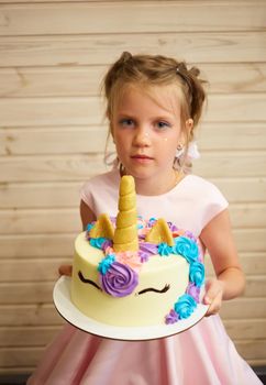 girl holding a cake in the form of a Unicorn.