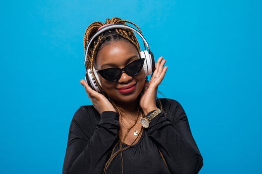 Stylish sunglasses. A dark-skinned student listens to music on wireless headphones. Musical relaxation.