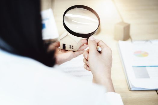 Inspector Concept, a customer is holding a magnifying glass to look at each house model to check the price of a home loan for each model