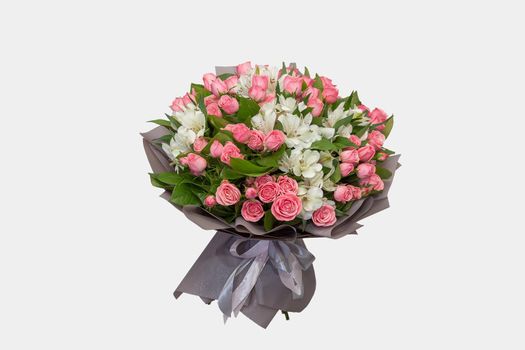 A festively wrapped bouquet with red and white flowers. The concept of floristry and congratulatory bouquets.