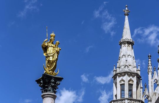 The statue of the Mariensäule on Marienplatz in Munich. The Mariensäule is a golden colored statue depicting the Madonna and Child Jesus standing on a crescent moon