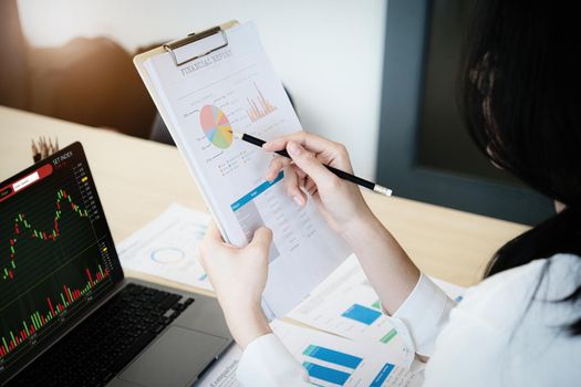 Business owner holding a pencil pointing to financial documents to analyze the profits of third parties to invest in company stocks