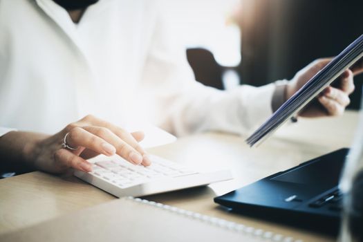 Business woman using calculator to review balance sheet annual using document and laptop computer to calculating budget. audit and Check integrity before investment concept