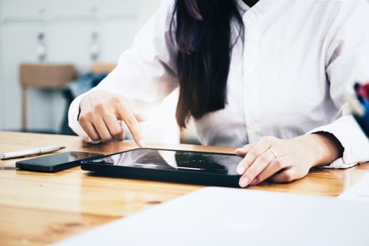 New normal, self-employed women are using a tablet to trade stocks for profit, buying and selling