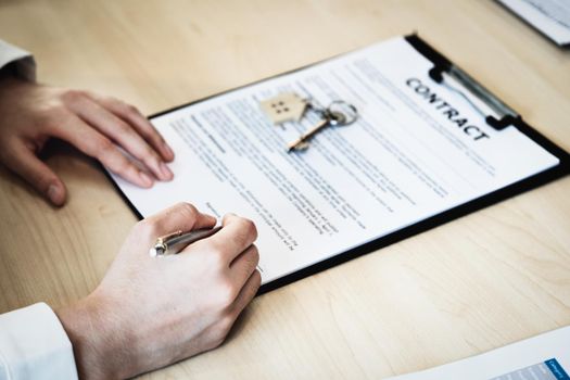 The customer is holding a pen and is reading the housing purchase contract before signing it