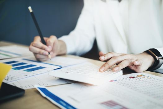 Business woman using calculator to review balance sheet annual using document and laptop computer to calculating budget. audit and Check integrity before investment concept