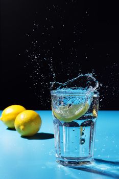 Water splash with lemon on blue and black background