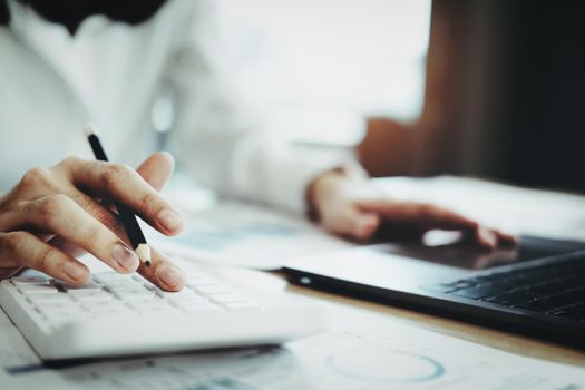 Business woman using calculator to review balance sheet annual using document and laptop computer to calculating budget. audit and Check integrity before investment concept