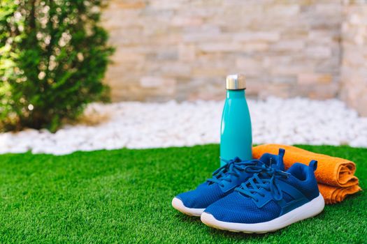 Close-up of objects and accessories to practise sports on green grass field. weights, towel, bottle of water. concept of practising sport outdoors. natural outdoor light.