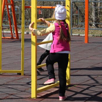 Children on a sunny day play in the playground, equipped with sports equipment..