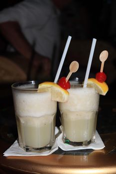 Big glass with a pina colada cocktail, decorated with a wooden stirrer and fresh fruit. Cruise ship cocktail