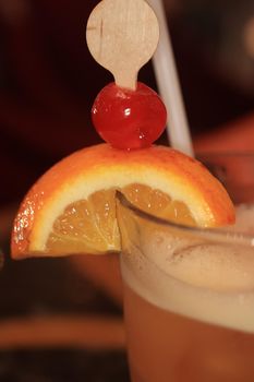 Big glass with a fruity cocktail, decorated with a wooden stirrer and fresh fruit. Cruise ship cocktail