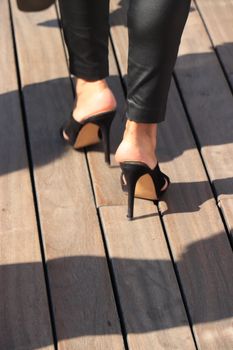 A woman walking on stiletto heels on a wooden jetty