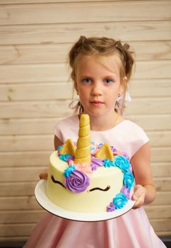 girl holding a cake in the form of a Unicorn.