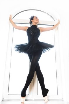 Young ballet dancer practicing before performance in black tutu, classical dance studio, copy space