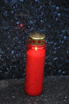 a red, burning candle on a grave