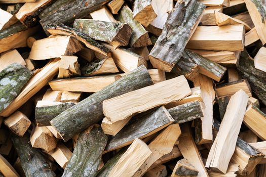 Stock of firewood for heating the house. The trees were cut down and split into firewood for use as fuel in fireplaces and stoves, with a background of firewood