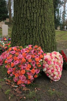 Heart shaped sympathy or funeral flowers near a tree