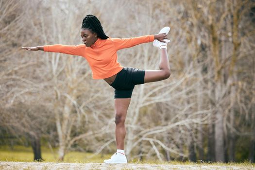 Finding my balance. Full length shot of an attractive young woman standing and stretching before exercising outdoors