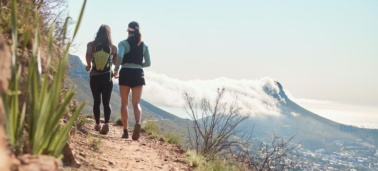 We will finish this trail together. Rearview shot of two young women running along a trail on the mountain