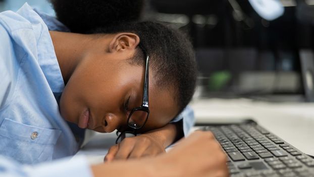 African young woman sleeping at work desk