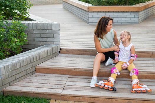 Caucasian woman teaches her daughter to skate on roller skates