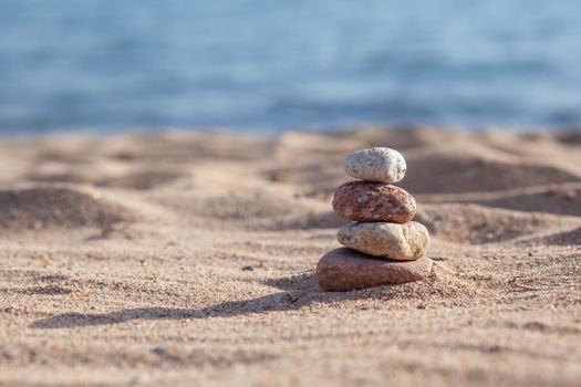 Round stones lie on top of each other in a column on the seashore on a sunny summer day. The concept of order and tranquility