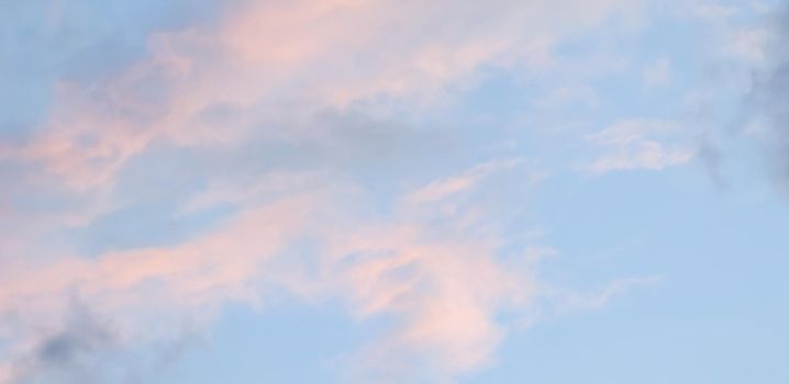 Background of blue sky with pale pink clouds at sunset