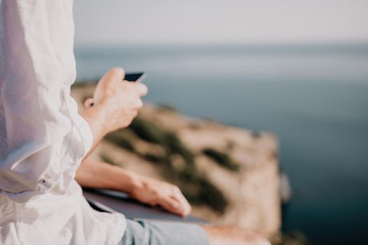 freelancer businessman working remotely on laptop at the beach near the sea