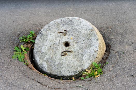 An old sewer manhole with an open concrete cover.