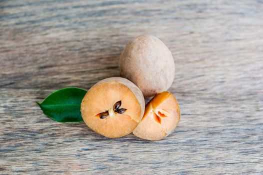 fresh sapodilla fruits on old wooden background. tropical fruits concept