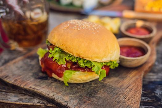 Closeup of fresh burger with French fries on wooden table with bowls of tomato sauce. lifestyle food.