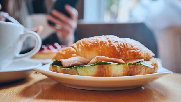 Croissant and meat on a girl's table at lunchtime