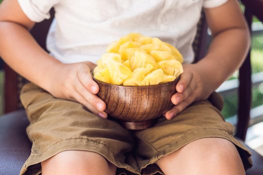 A boy eating a pineapple on the terrace.