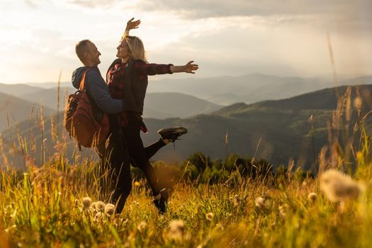 Happy traveler young couple resting in the mountains at sunset in spring or summer season