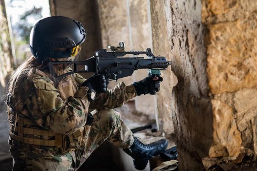 A woman in an army uniform shoots a firearm in an abandoned building