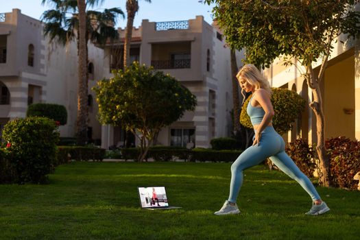 Young fitness woman enjoying warm sunny day in yard of resort hotel. Tourism, vacation and weekend