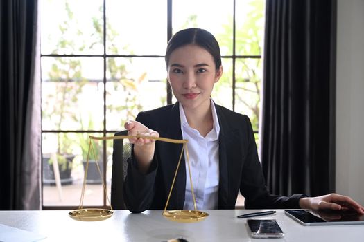 Female lawyers holding brass scale and looking confidently to camera. Lawyer, justice and law and attorney concept.