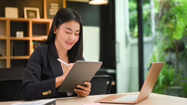 Charming businesswoman working with modern devices at her personal office.