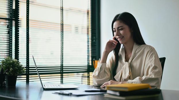 Pleasant young woman entrepreneur working on laptop computer at modern workplace.